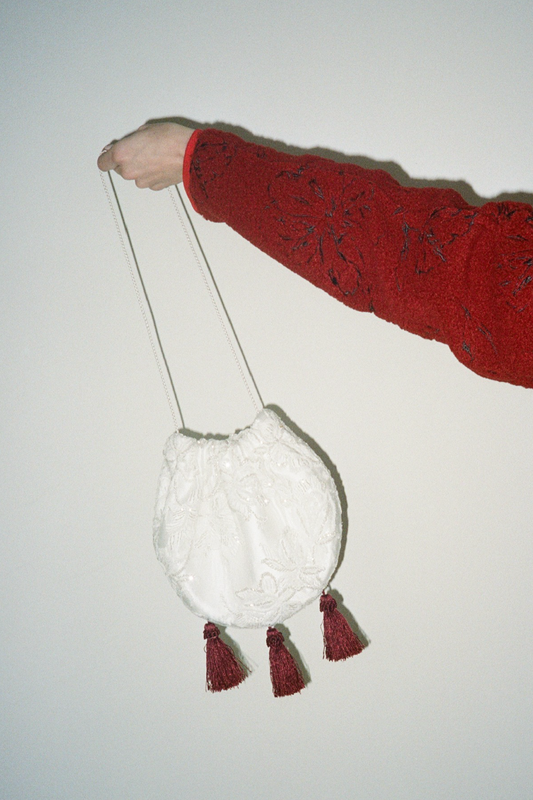 Person holding a lace bag with red tassels 
